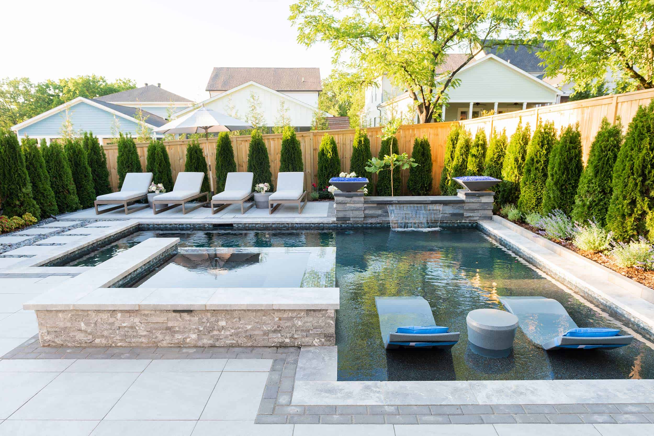 L-shaped swimming pool surrounded by lush landscaping